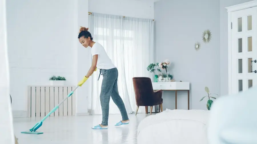 A cleaner mopping a bright living room floor